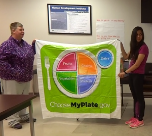 Brandy and Monica co-facilitators of the Health Partners program hold up the MyPlate mat for a food matching game